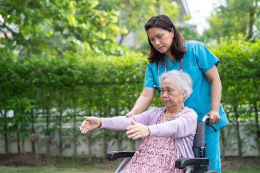 Doctor help Asian senior or elderly old lady woman patient exercise on wheelchair with happy in park.