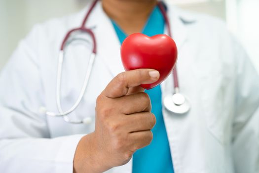 Doctor holding a red heart in hospital ward, healthy strong medical concept.