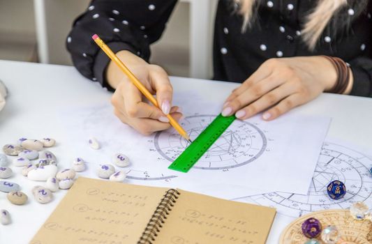 Woman astrologer draws a natal chart. Selective focus. People.