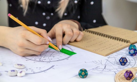 Woman astrologer draws a natal chart. Selective focus. People.