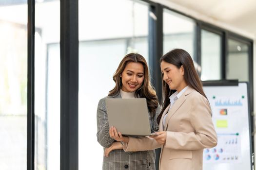 Young colleagues discuss business and analytical price charts using calculators and laptops to calculate financial, tax, accounting, statistics and analytical research.