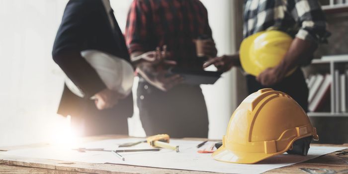 Civil engineer teams meeting working together wear worker helmets hardhat on construction site in modern city. Foreman industry project manager engineer teamwork. Asian industry professional team...