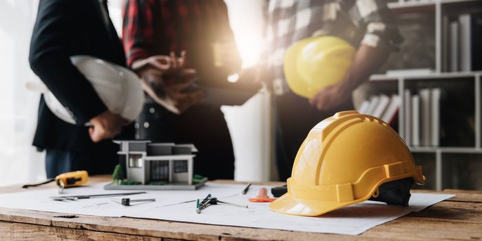 Civil engineer teams meeting working together wear worker helmets hardhat on construction site in modern city. Foreman industry project manager engineer teamwork. Asian industry professional team...