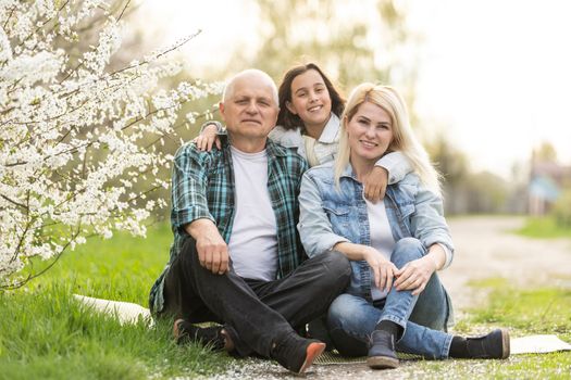Three generation family sitting outside in spring nature.