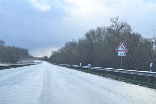 Wet highway with trees at the side against a dramatic sky