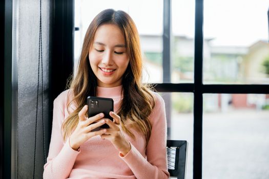 Asian young woman hands holding mobile phone at cafe coffee shop, Happy beautiful female typing text message on smart phone device and enjoyment lifestyle with social networking media