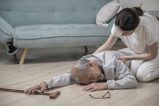 Asia young woman halping her father after falling down on floor, elderly old man with walking stick fall on ground and daughter camp to help at home in living room, family health care