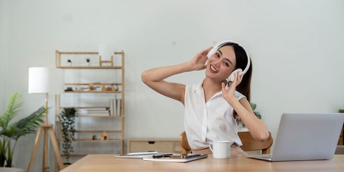 portrait of young smiling asian woman in headphones listening to music at home.