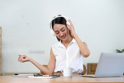 portrait of young smiling asian woman in headphones listening to music at home.