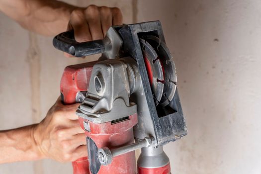 professional construction power tool for cutting strob in the hands of a worker during the renovation of the apartment. A hand-held power tool with two diamond discs for cutting grooves in the wall for laying electrics. Professional tool. Close-up