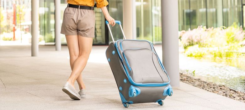 Traveler suitcase, woman carrying a suitcase in a travel location on holidays trip with lens flare technique, traveling on holidays concepts.