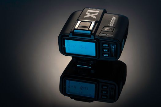 Sosnovy Bor, RUSSIA - January 02, 2023: Godox XT2 remote radio synchronizer for flash control. close-up with reflection on black glass. professional Photo Equipment