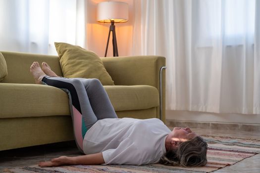 senior woman doing warmup workout at home. Fitness woman doing stretch exercise stretching her body. Elderly woman living an active lifestyle.