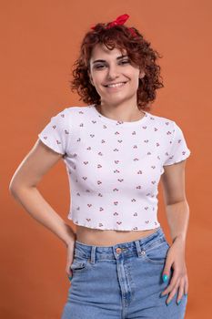 Attractive young girl with a beautiful smile one hundred and one brick-colored background. White blouse with cherry pattern.