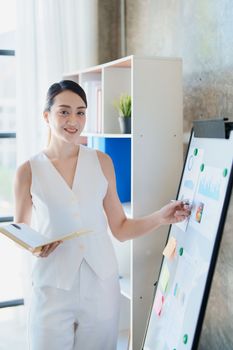 Portrait of young asian woman holding notebook with presentation of strategy, investment plan and marketing