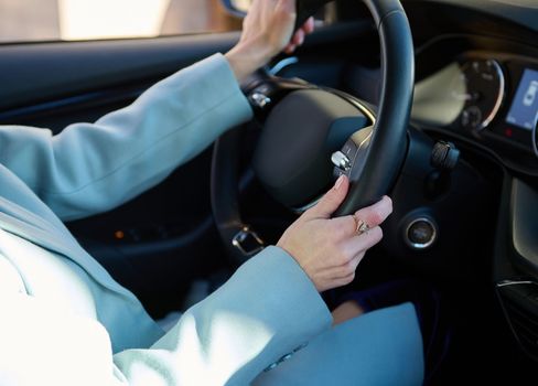 Close-up of female driver's hands on the steering wheel of modern comfortable automobile while driving car in city road. Car insurance policy. People. Urban lifestyle and Safety driving concept