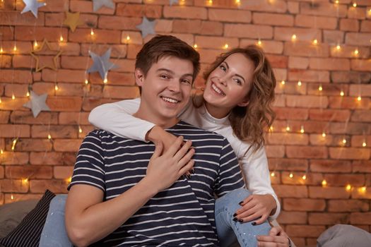 Relation emotions. Young man embracing attractive brunette wife indoor. They are in love and happy