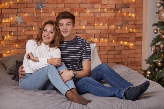 Young man and woman tenderly embracing in bedroom on the bed, they show tenderness to each other