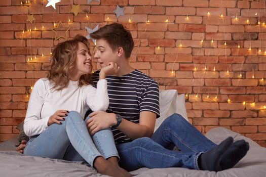 Young man and woman tenderly embracing in bedroom on the bed, they show tenderness to each other