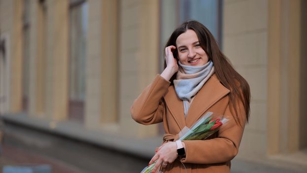Portrait of a happy girl with a tulip on the city street