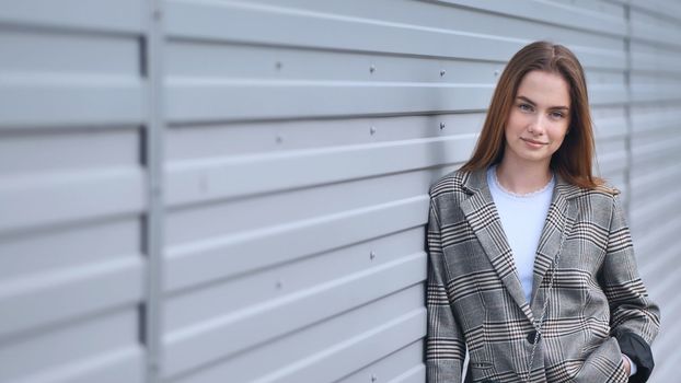 Portrait of a young girl in a blazer by a wall on the street