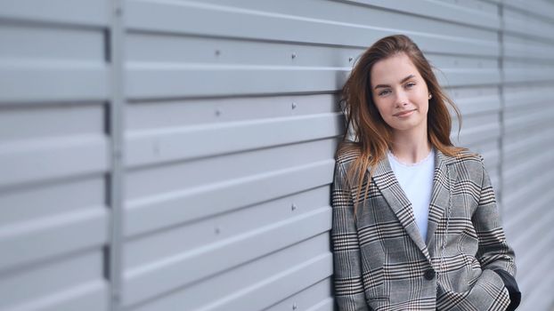 Portrait of a young business girl against a wall on the street