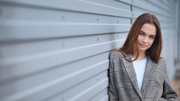 Portrait of a young girl in a blazer by a wall on the street