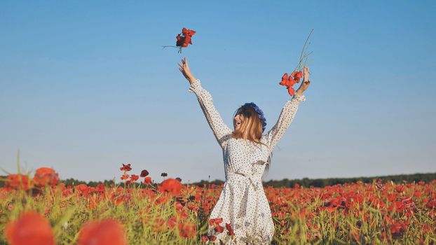 Ukrainian girl tosses poppy flowers in a poppy field