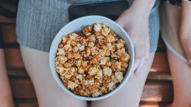 Friends eating popcorn on the street. Close-up of hands
