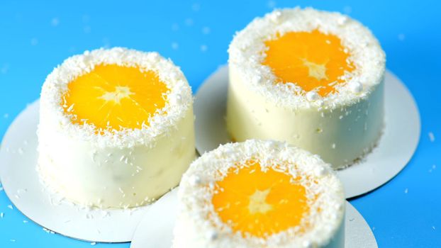 Small cakes with orange and coconut on a blue background