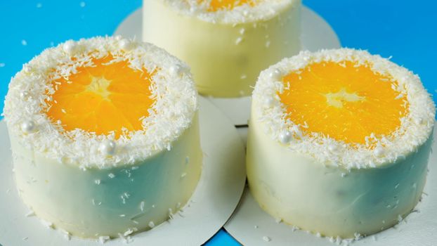 Small cakes with orange and coconut on a blue background