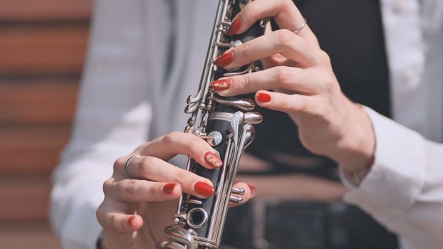 A girl plays the clarinet in the park in the summer