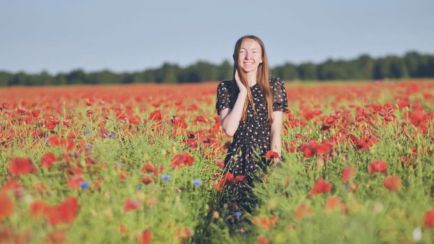 A young girl walks through a red poppy field