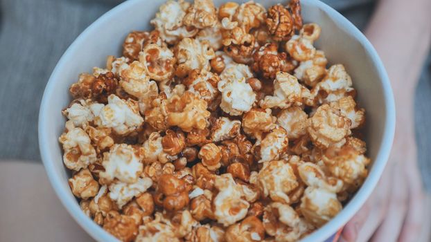 Girl eating popcorn on the street. Close-up of hands