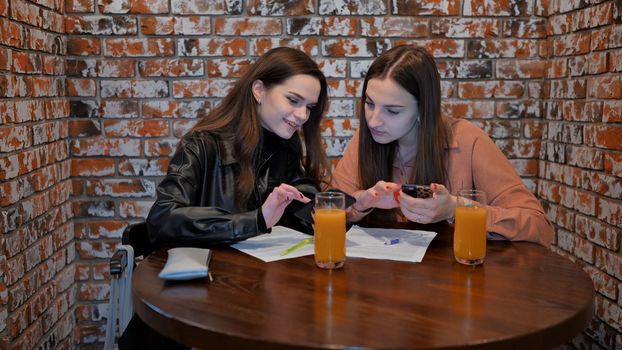 Two girls are working in a cafe with documents