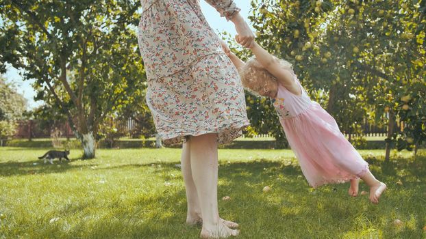 A mother circles her daughter in the garden outside the house