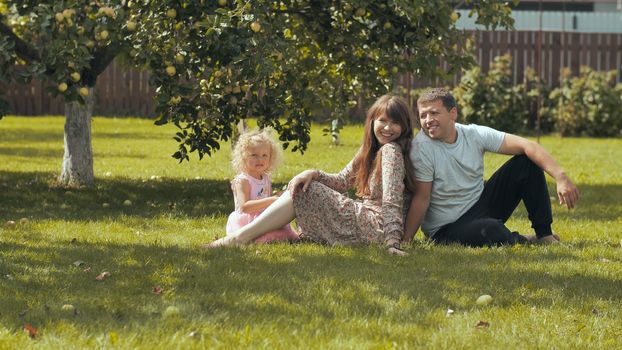 A young family on the grass in the garden outside their home