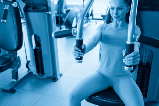 Torso portrait of Cheerful young adult caucasian woman working out on exercise machine inside a gym