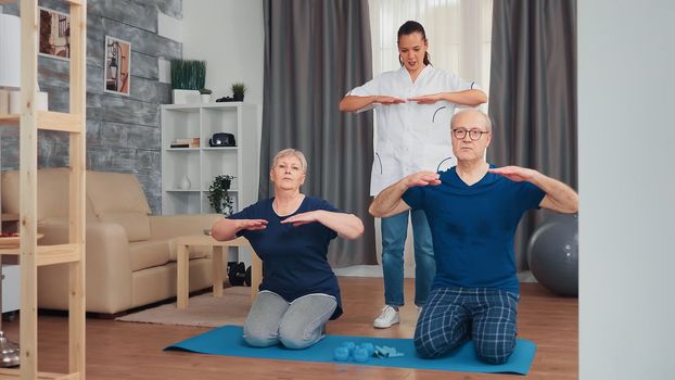 Senior couple doing physical therapy with doctor at home. Home assistance, physiotherapy, healthy lifestyle for old person, training and healthy lifestyle