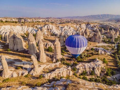 Colorful hot air balloons flying over at fairy chimneys valley in Nevsehir, Goreme, Cappadocia Turkey. Spectacular panoramic drone view of the underground city and ballooning tourism. High quality.