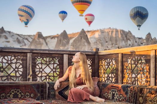 Tourist woman looking at hot air balloons in Cappadocia, Turkey. Happy Travel in Turkey concept. Woman on a mountain top enjoying wonderful view.