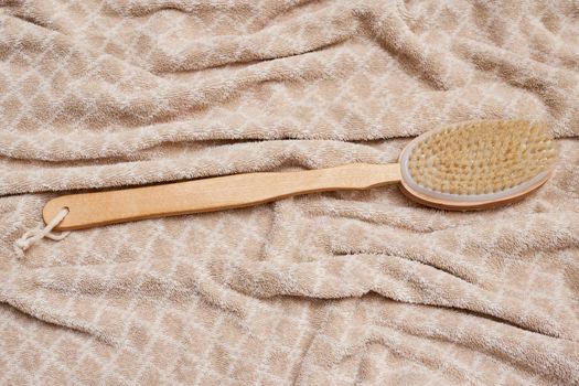 a wooden tooth brush on a bed with a white and beige blanket in the background, as seen from above