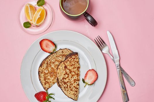 a plate of pancakes with strawberries on it and a cup of coffee next to the plate is pink background