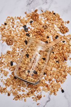 granos in a glass jar on a white marble countertopped with blueberries and almonds scattered around