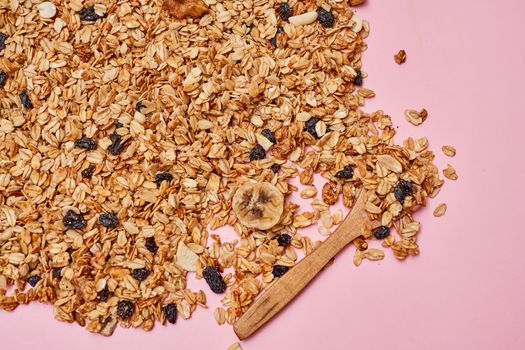oats on a pink surface with a wooden spoon in the background and an image of blueberries, almonds, and nuts