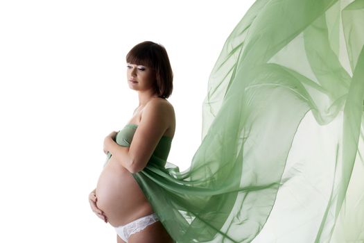 Pretty pregnant woman with green blowing fabric. Isolated on white