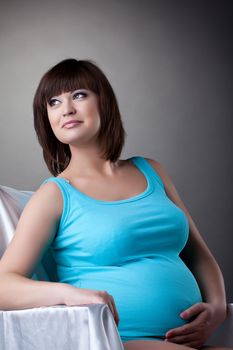 Studio portrait happy pregnant brunette young woman in blue underwear