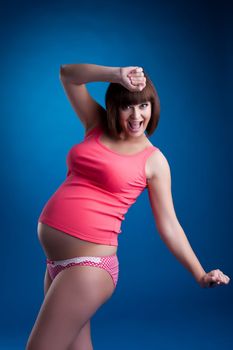 Studio portrait happy pregnant brunette young woman in pink underwear