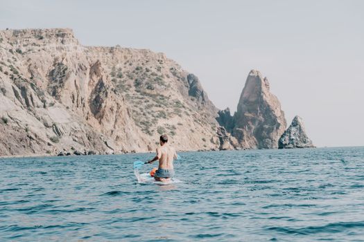 Side view foto of a man swiming and relaxing on the sup board. Sportive man in the sea on the Stand Up Paddle Board SUP. The concept of an active and healthy life in harmony with nature