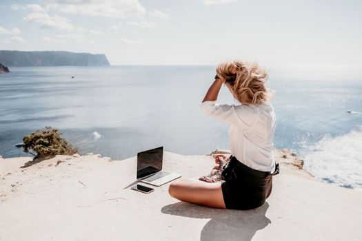 Happy girl doing yoga with laptop working at the beach. beautiful and calm business woman sitting with a laptop in a summer cafe in the lotus position meditating and relaxing. freelance girl remote work beach paradise